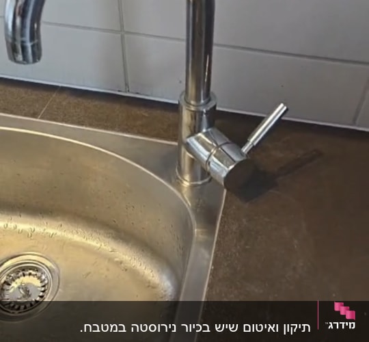 כיור נירוסטה וברז מותקנים במשטח שיש כהה במטבח
